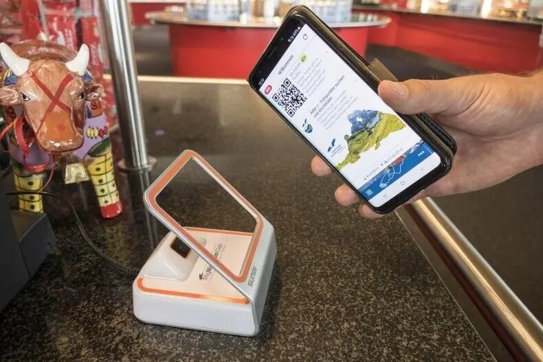 Hand hält Smartphone mit QR-Code über Ticketscanner am Trese