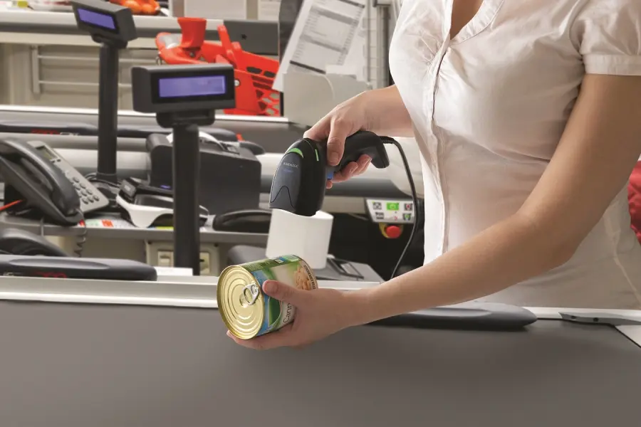 Mitarbeiterin scannt Konservendose mit Handscanner an Kasse