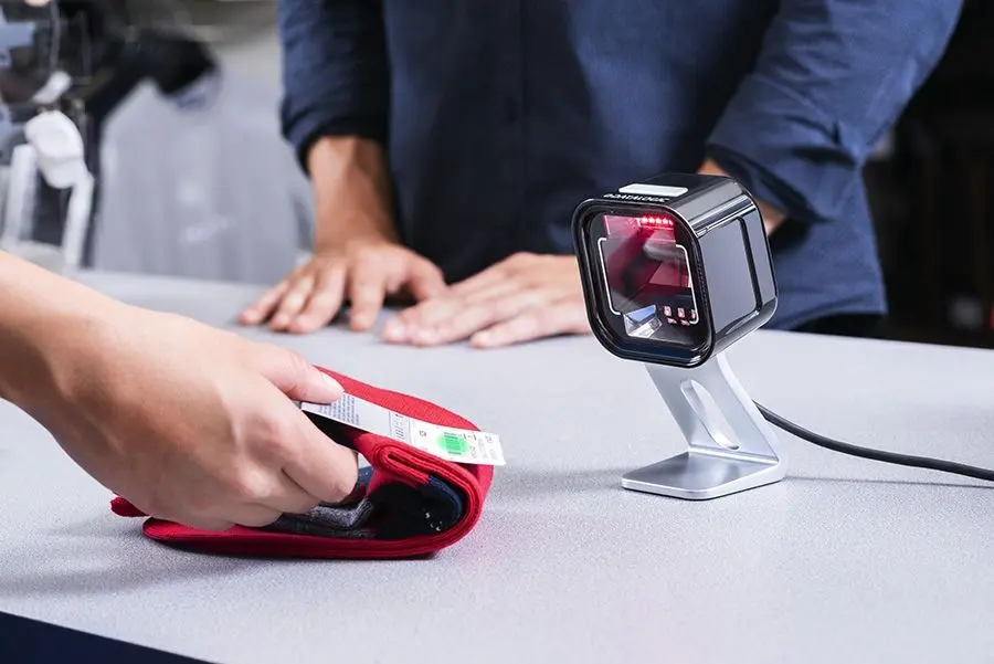 Kompakter Barcodescanner scannt Textiletikett an der Kasse