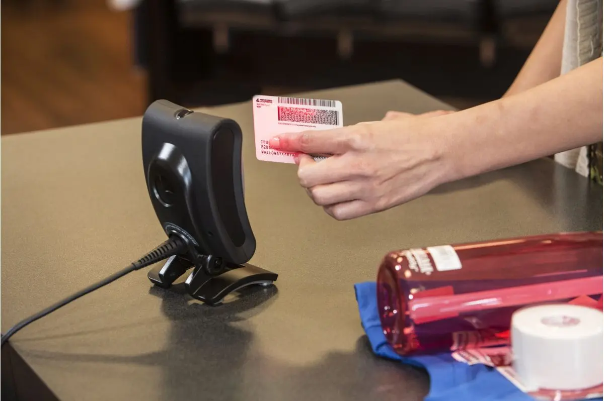 Hand scannt Kundenkarte an stationärem Barcodescanner