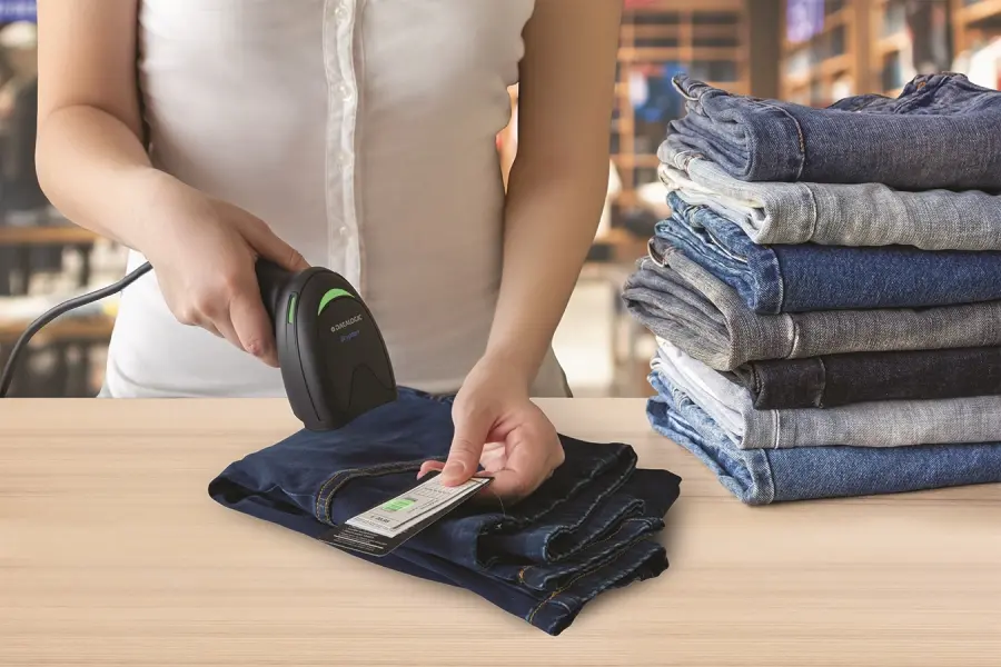 Mitarbeiterin scannt Etikett einer Jeans mit Barcode-Scanner